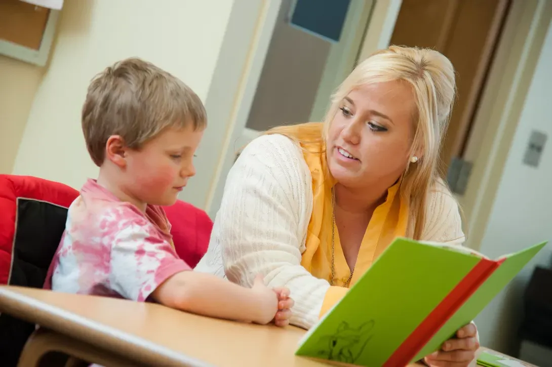 Student teacher reading with student in classroom